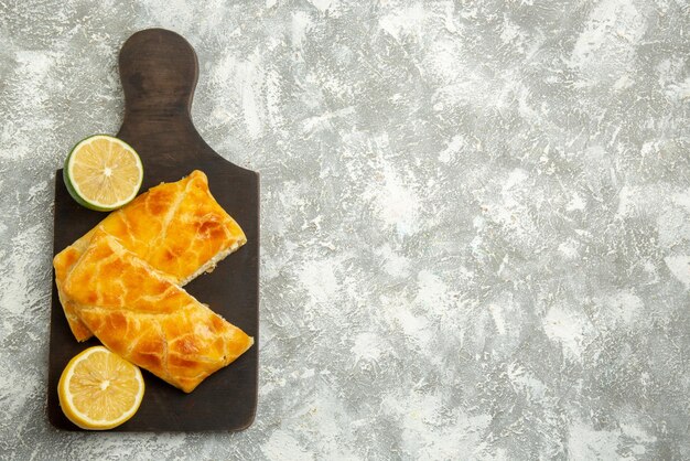 Top view from afar pies on board appetizing pies lemon and lime on the dark wooden cutting board on the left side of the table