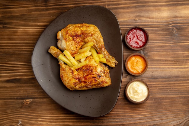 나무 탁자에 있는 식욕을 돋우는 감자튀김과 닭다리 옆에 다채로운 소스가 담긴 패스트푸드 그릇의 멀리 있는 전망