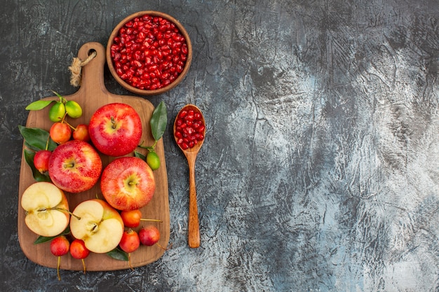 Top view from afar pomegranate pomegranate seeds spoon the board of apples cherries