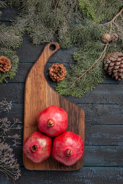 Top view from afar pomegranates on board pomegranates on the kitchen board and branches with cones