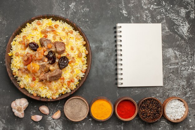 Top view from afar rice pilaf spices garlic notebook on the table