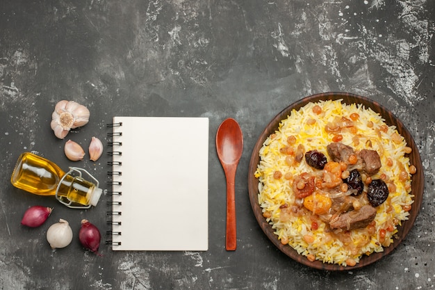 Free photo top view from afar rice pilaf with meat onion garlic bottle of oil spoon notebook