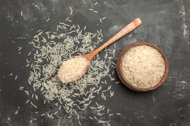 Top view from afar rice rice in the spoon and bowl on the dark table