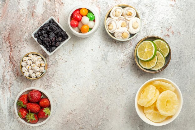 Top view from afar sweets bowls of berries sweets and dried pineapples are laid out in a circle