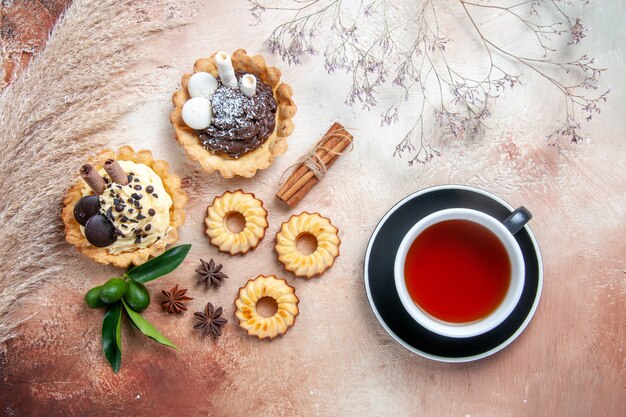 Top view from afar sweets cinnamon cupcakes cookies citrus fruits star anise a cup of tea