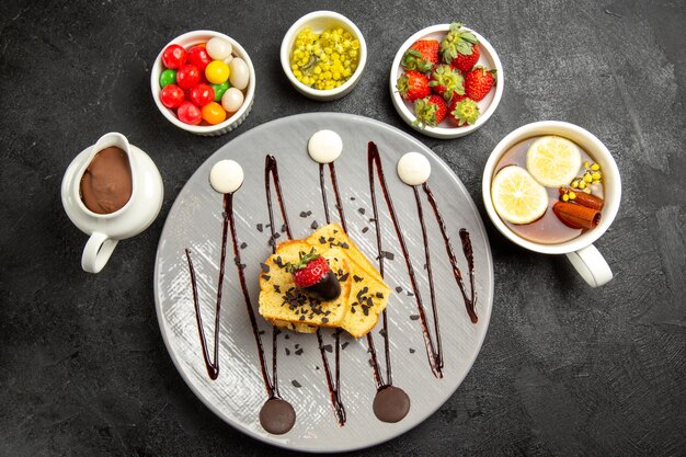 딸기와 초콜릿이 든 케이크 조각과 과자와 딸기, 레몬이 든 차 한 잔을 곁들인 맛있는 디저트 접시에서 가장 높은 전망