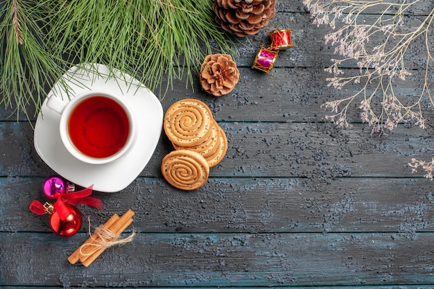 Free photo top view from afar tea spruce tree with cones and christmas toys cinnamon sticks and a cup of tea on the saucer