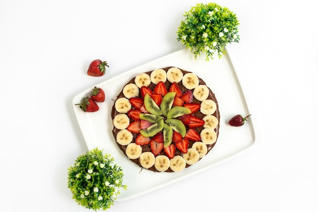 Una torta al cioccolato con vista dall'alto progettata con fragole fresche di banane e kiwi all'interno del dessert dolce con zucchero bianco