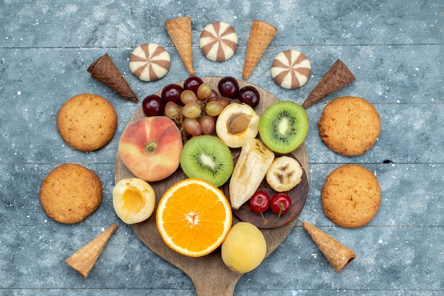 Бесплатное фото Вид сверху нарезанный и целый фруктовый состав с печеньем на ярком столе фруктовый экзотическое печенье сахар