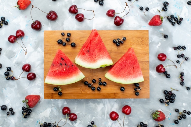 Una composizione di frutta vista dall'alto ha affettato l'anguria con frutta fresca su bianco, colore della frutta pastoso