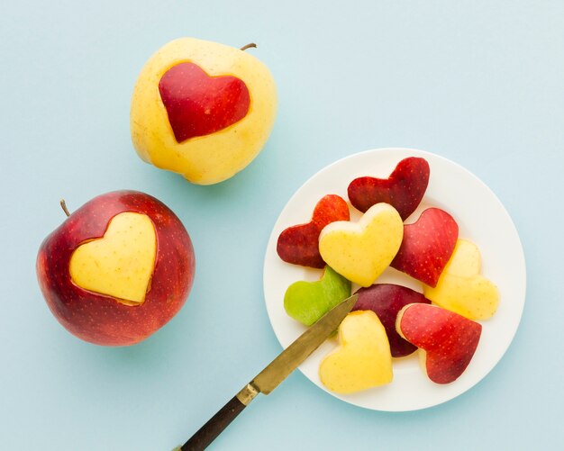 Top view of fruit heart shapes on plate with knife