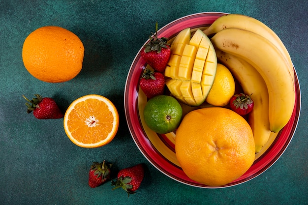 Foto gratuita vista dall'alto mix di frutta in un piatto di mango fragola lime e arancio su verde