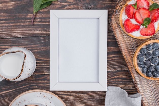 Top view of fruit tarts with frame and cream