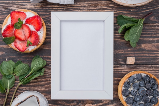 Top view of fruit tarts with frame and mint