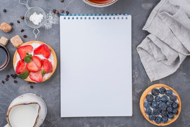 Top view of fruit tarts with notebook