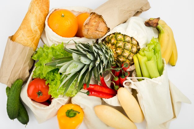 Top view of fruit and vegetables in reusable bags with bread