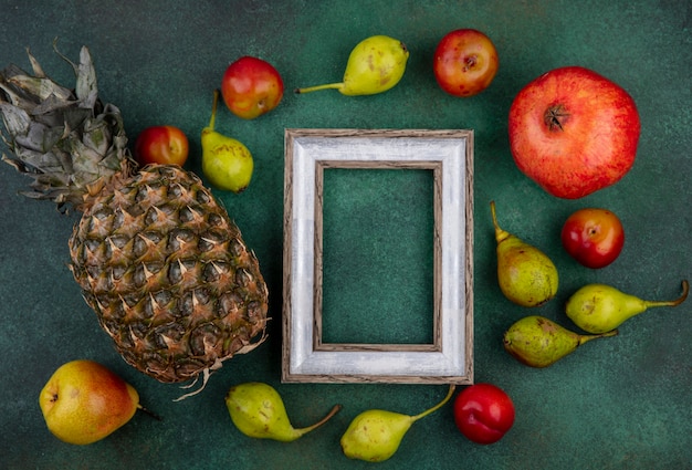 Free photo top view of fruits around frame on green surface