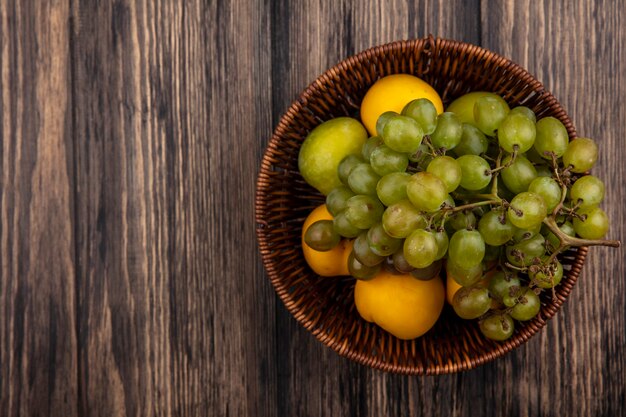 복사 공간 나무 배경에 바구니에 nectacots 녹색 pluots 포도로 과일의 상위 뷰