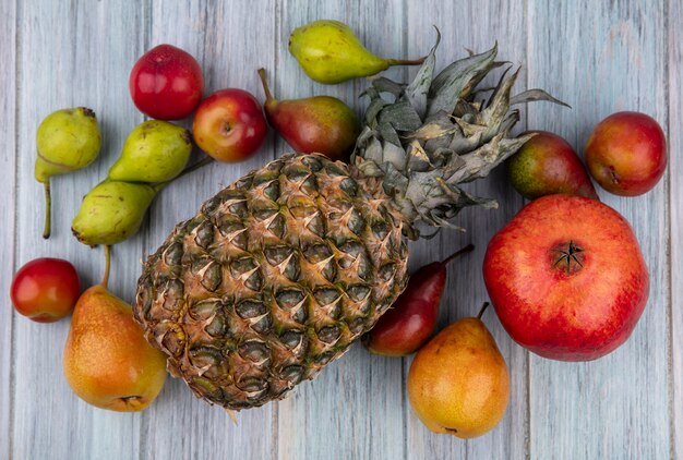 Top view of fruits as pineapple peach plum pomegranate on wooden surface