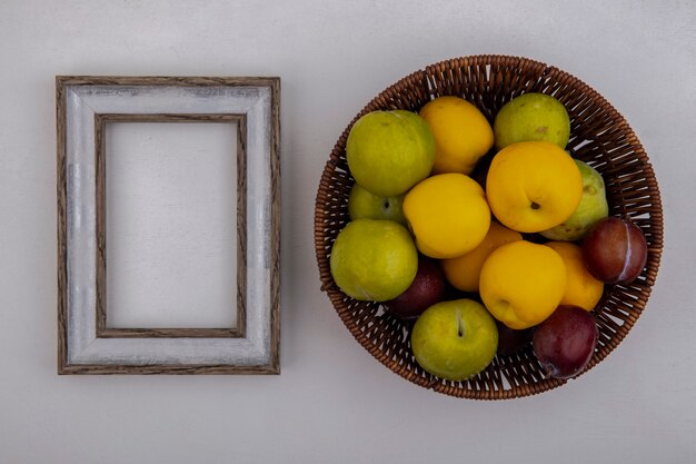 Top view of fruits as pluots and nectacots in basket with frame on white background with copy space