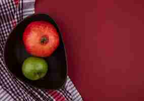 Free photo top view of fruits as pomegranate and apple in plate on plaid cloth and bordo surface