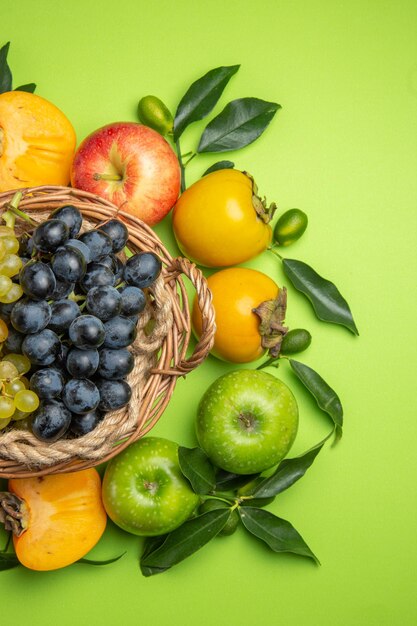 Top view fruits basket of bunches of grapes persimmons apples with leaves