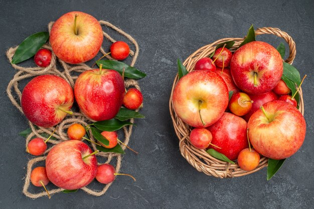 Top view fruits basket with fruits and the appetizing apples cherries with leaves rope