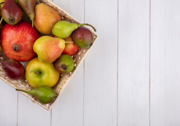 Top view of fruits in basket on wooden surface with copy space