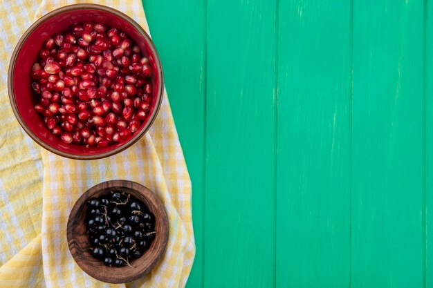 Top view of fruits in bowls on plaid cloth on green surface