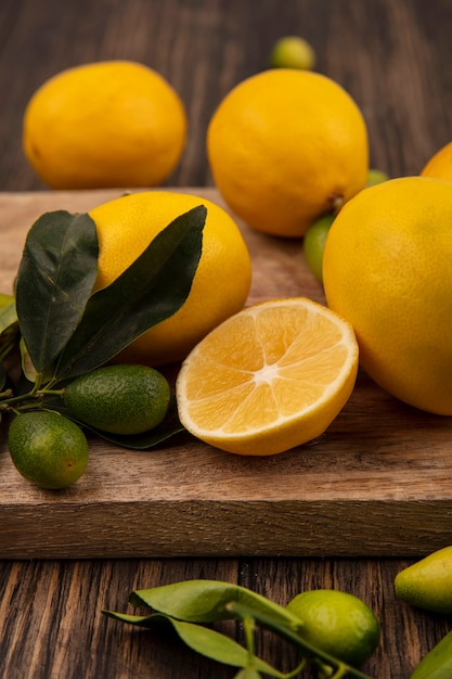 나무 벽에 나무 주방 보드에 고립 된 kinkans 및 레몬과 같은 과일의 상위 뷰