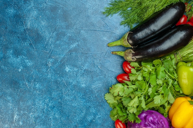 Foto gratuita vista dall'alto frutta e verdura pomodorini melanzane cavolo rosso coriandolo sul tavolo blu con spazio libero