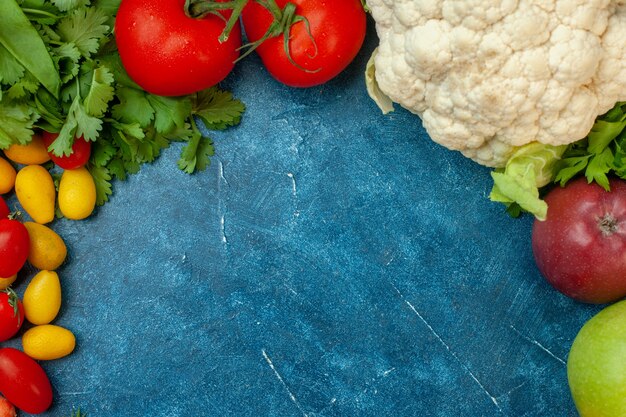 Top view fruits and vegetables parsley cherry tomatoes cumcuat cauliflower apples tomatoes on blue background