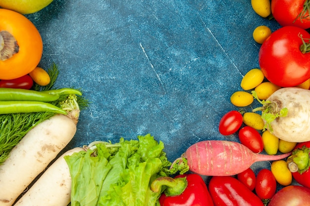 Top view fruits and vegetables radish cherry tomato cumcuat persimmon tomatoes lettuce on blue table free space