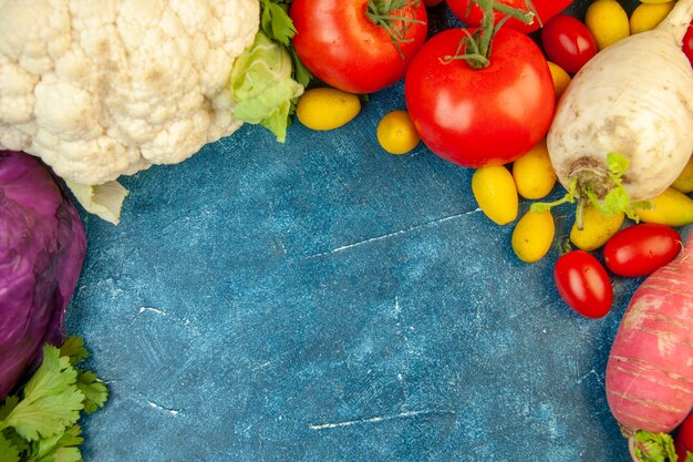 Top view fruits and vegetables red cabbage cherry tomato cumcuat tomato radish cauliflower on blue table