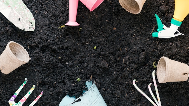 Top view of gardening equipments arranged on black soil