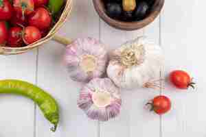 Free photo top view of garlic bulbs with olives, pepper and cherry tomatoes on wooden surface