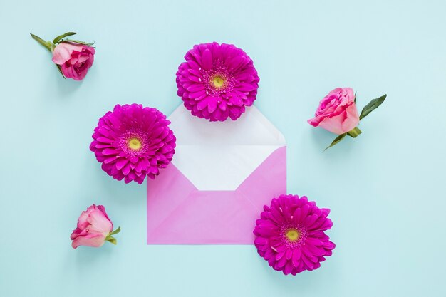 Top view gerbera and rose flowers and envelope