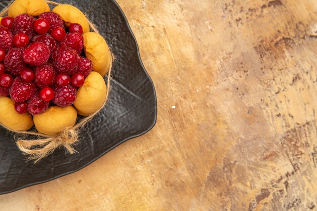 Top view of a gift cake with fruits on the right side of mixed color background