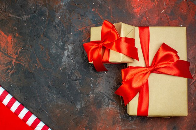 Top view gifts tied with red ribbon on dark red table copy space