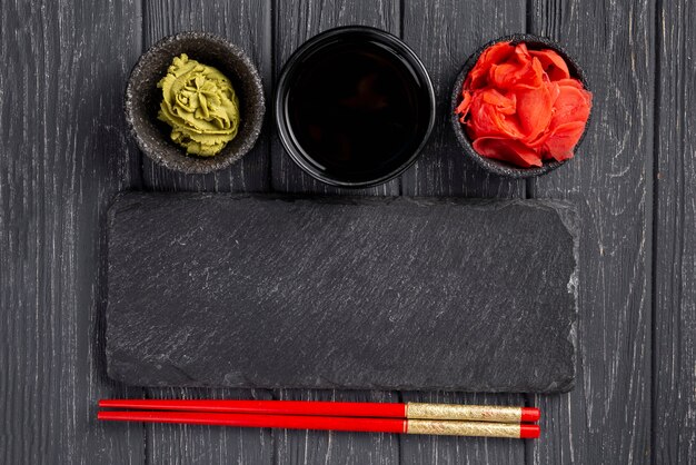 Top view ginger wasabi and soy sauce bowls and chopsticks