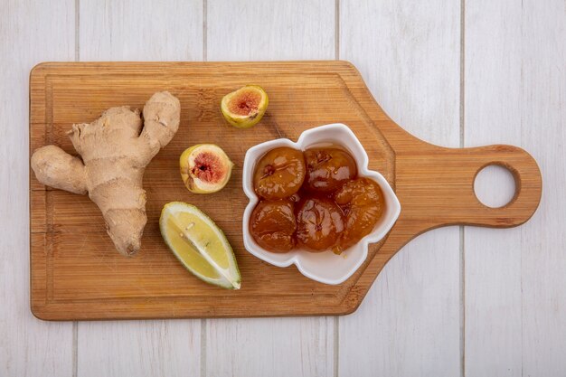 Top view ginger with lemon slice and fig jam in a saucer on a cutting board  on white background