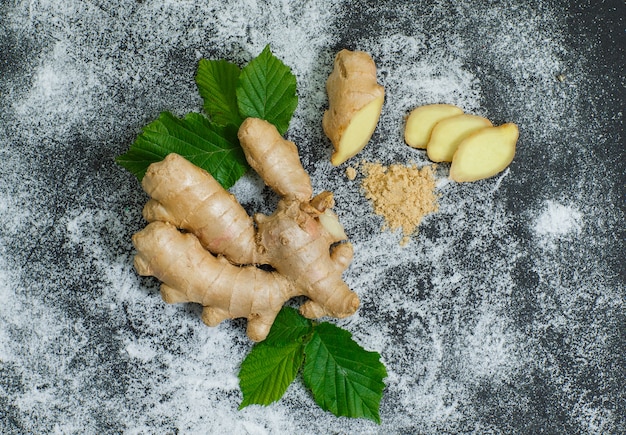 Free photo top view ginger with slices and leaves on gray textured surface. horizontal