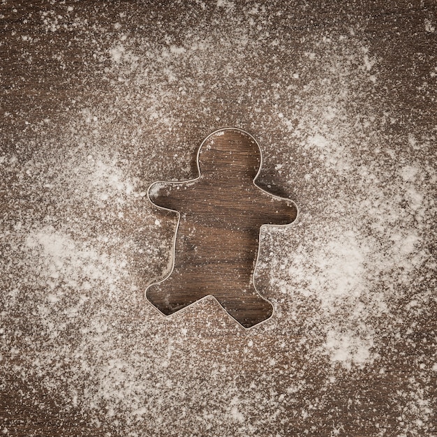 Free photo top view gingerbread man cookie cutter with flour