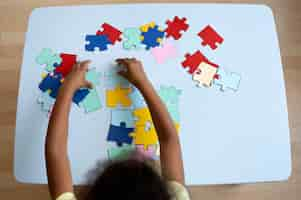 Free photo top view girl making puzzle at table