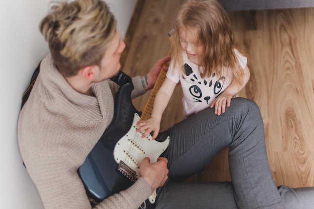 彼女の父のギターに触れる女の子のトップビュー