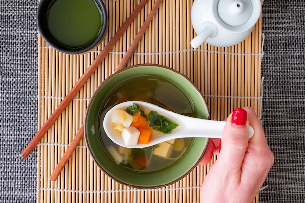 Foto gratuita vista dall'alto di una ragazza con le unghie rosse che mangia una zuppa di miso