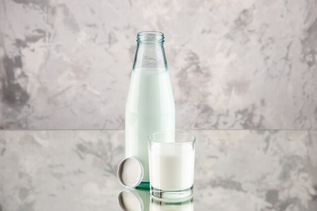 空きスペースのあるパステルカラーの背景にミルクキャップで満たされたガラス瓶とカップの上面図