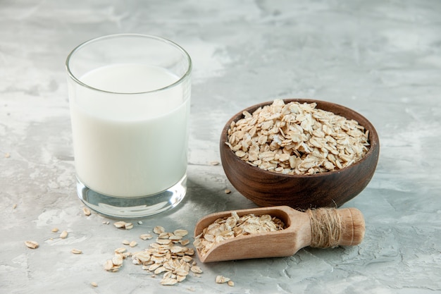 Top view of glass cup filled with milk and oats inside and outside the brown pot on white background