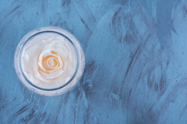 Top view of a glass cup with water and pink rose .