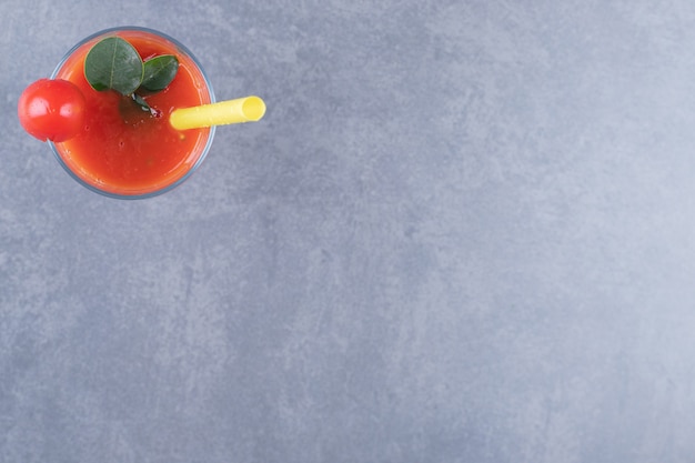 Top view. Glass of fresh tomato juice and tomatoes on a grey background.